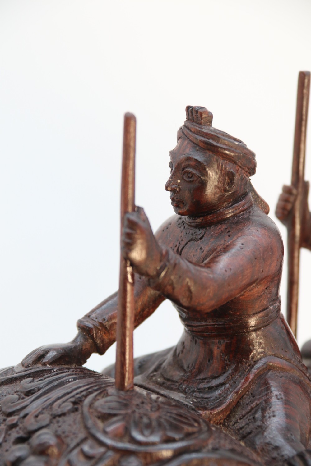 A dark hardwood sculpture depicting a ceremonial elephant adorned with decorative drapery accompanied by three mahouts on an integrated wooden base. View XIV