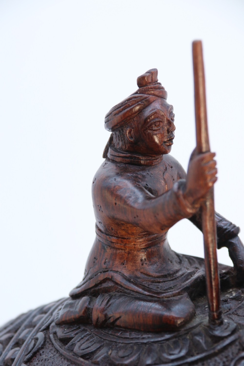 A dark hardwood sculpture depicting a ceremonial elephant adorned with decorative drapery accompanied by three mahouts on an integrated wooden base. View XV