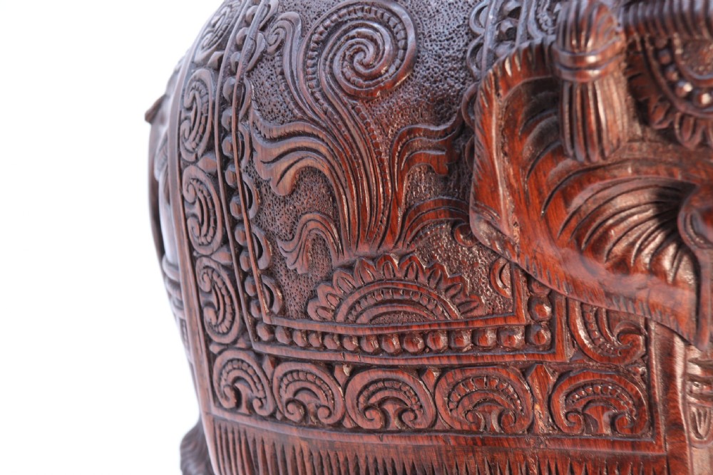 A dark hardwood sculpture depicting a ceremonial elephant adorned with decorative drapery accompanied by three mahouts on an integrated wooden base. View XVI