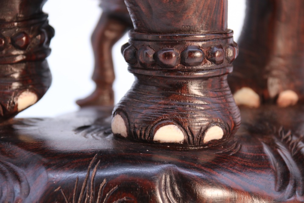 A dark hardwood sculpture depicting a ceremonial elephant adorned with decorative drapery accompanied by three mahouts on an integrated wooden base. View XVIII