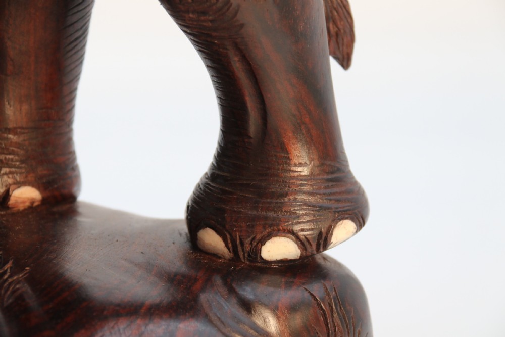 A dark hardwood sculpture depicting a ceremonial elephant adorned with decorative drapery accompanied by three mahouts on an integrated wooden base. View XIX