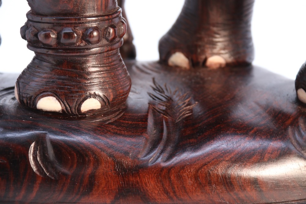 A dark hardwood sculpture depicting a ceremonial elephant adorned with decorative drapery accompanied by three mahouts on an integrated wooden base. View XXIII