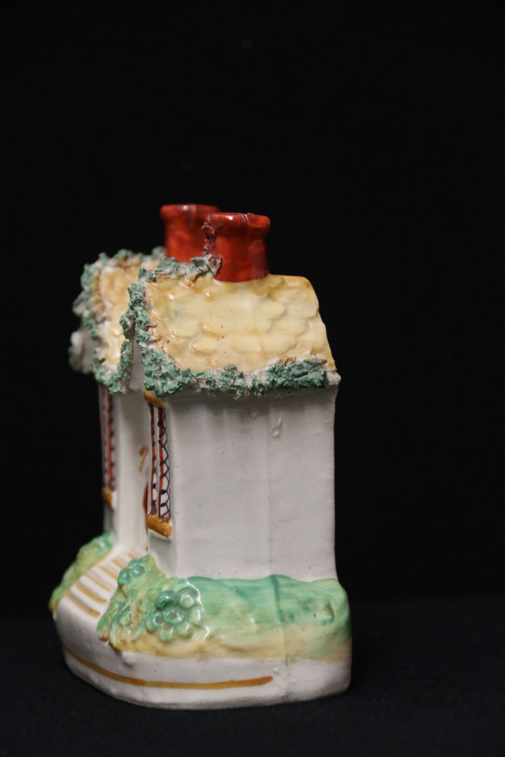 A 19th-century Staffordshire earthenware money box sculpted as a two-chimney cottage featuring applied shredded-clay foliage. View II