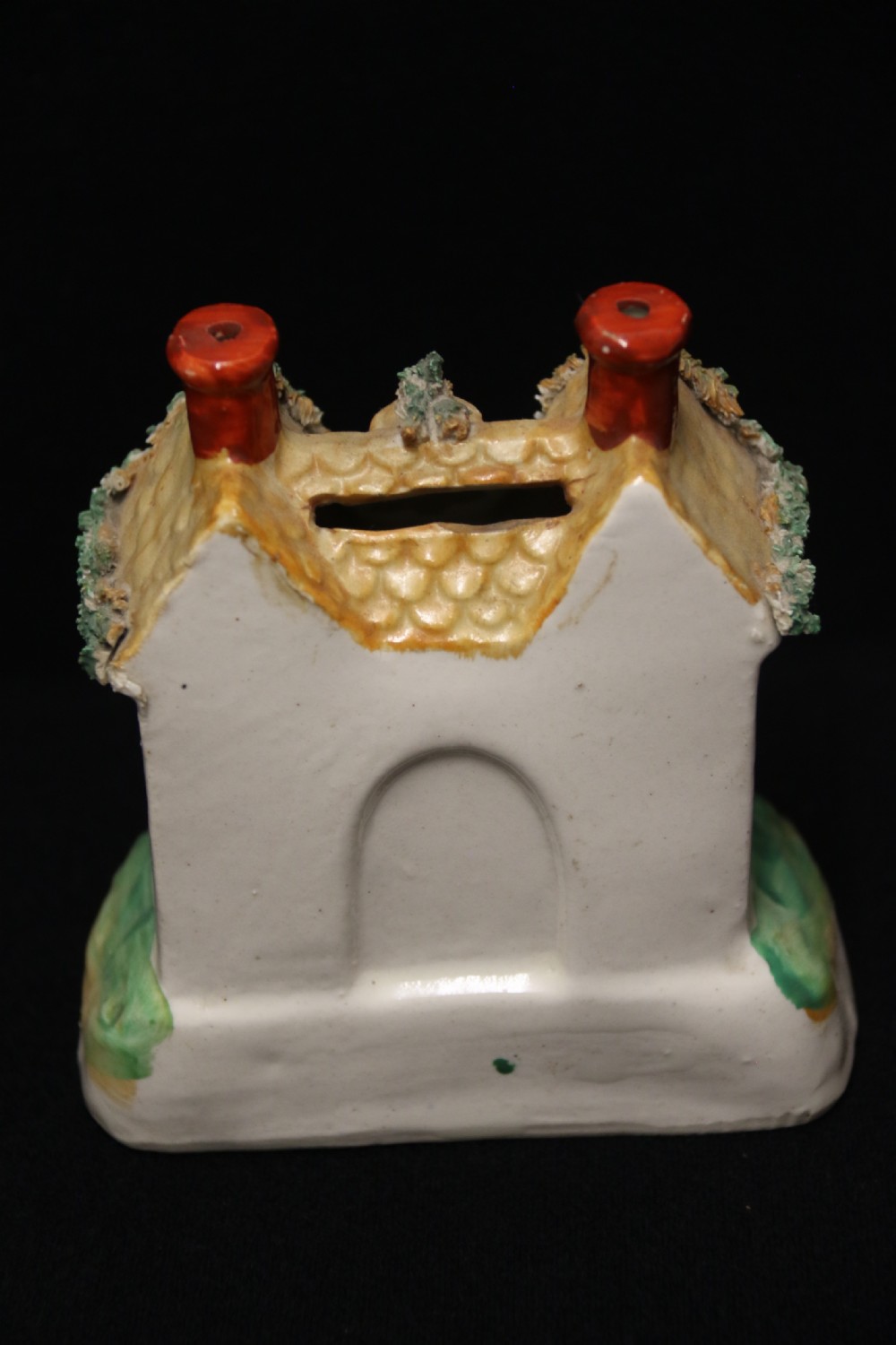 A 19th-century Staffordshire earthenware money box sculpted as a two-chimney cottage featuring applied shredded-clay foliage. View III