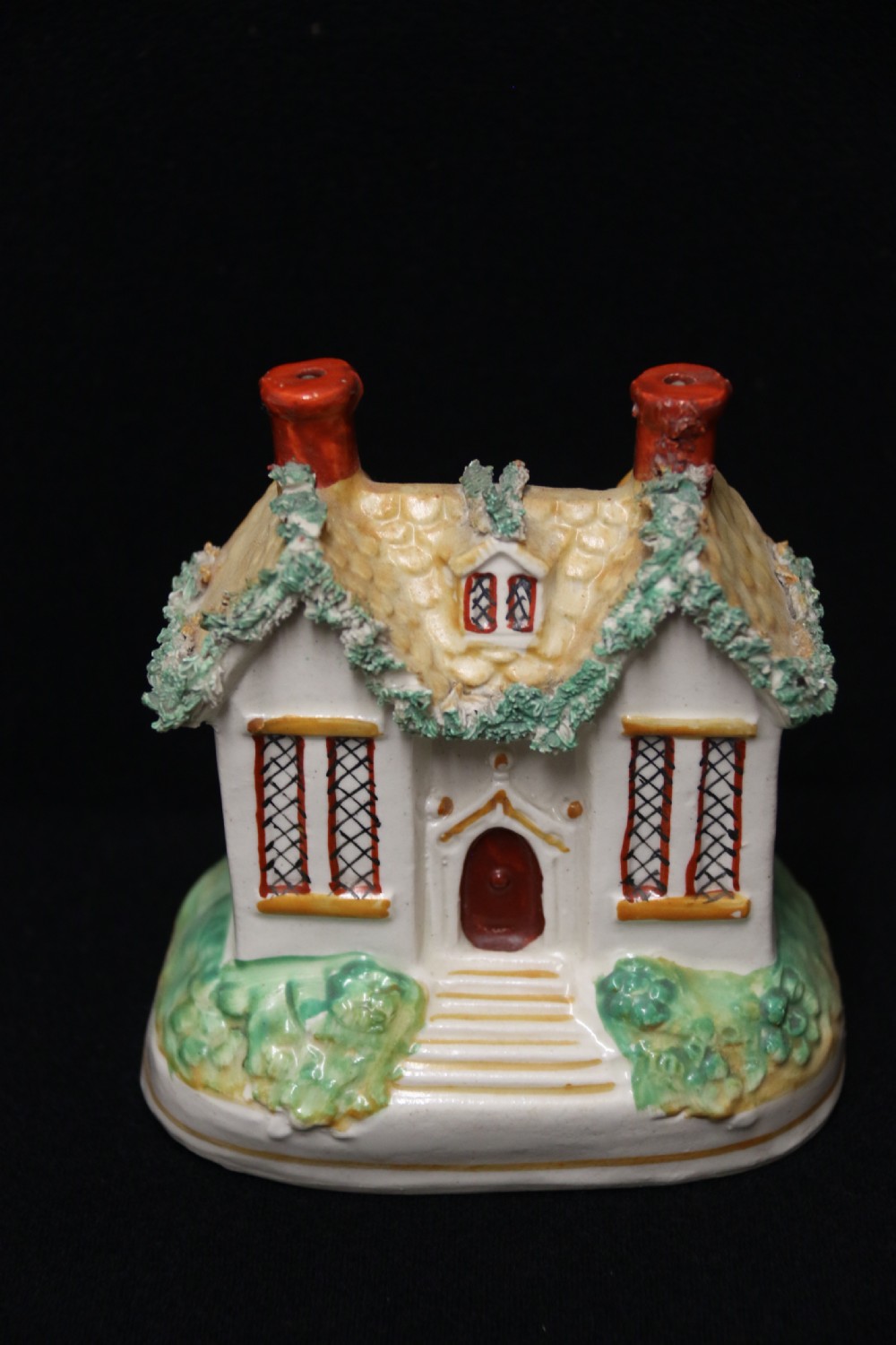 A 19th-century Staffordshire earthenware money box sculpted as a two-chimney cottage featuring applied shredded-clay foliage. View V