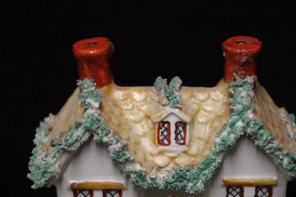 A 19th-century Staffordshire earthenware money box sculpted as a two-chimney cottage featuring applied shredded-clay foliage. View VII