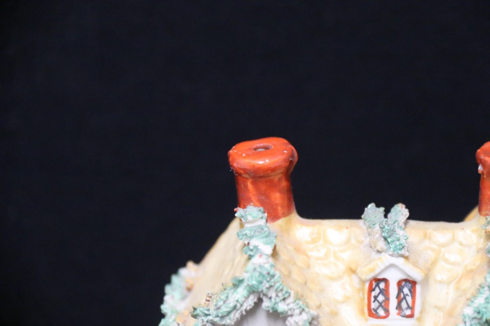 A 19th-century Staffordshire earthenware money box sculpted as a two-chimney cottage featuring applied shredded-clay foliage. View VIII