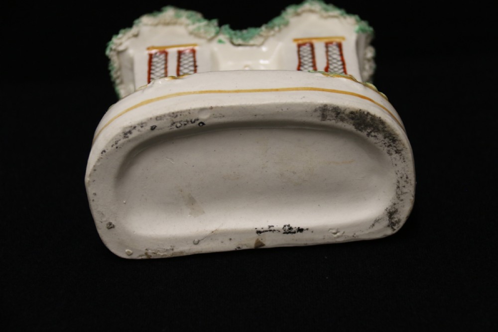 A 19th-century Staffordshire earthenware money box sculpted as a two-chimney cottage featuring applied shredded-clay foliage. View IX