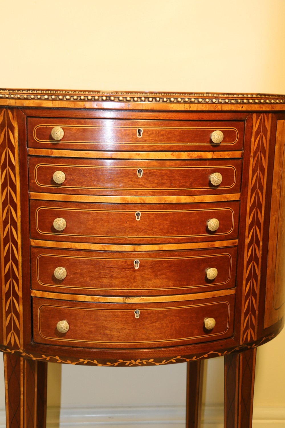 An oval George III satinwood worktable featuring marquetry inlay, multiple drawers, tapered legs, and a rising mirror compartment. View V