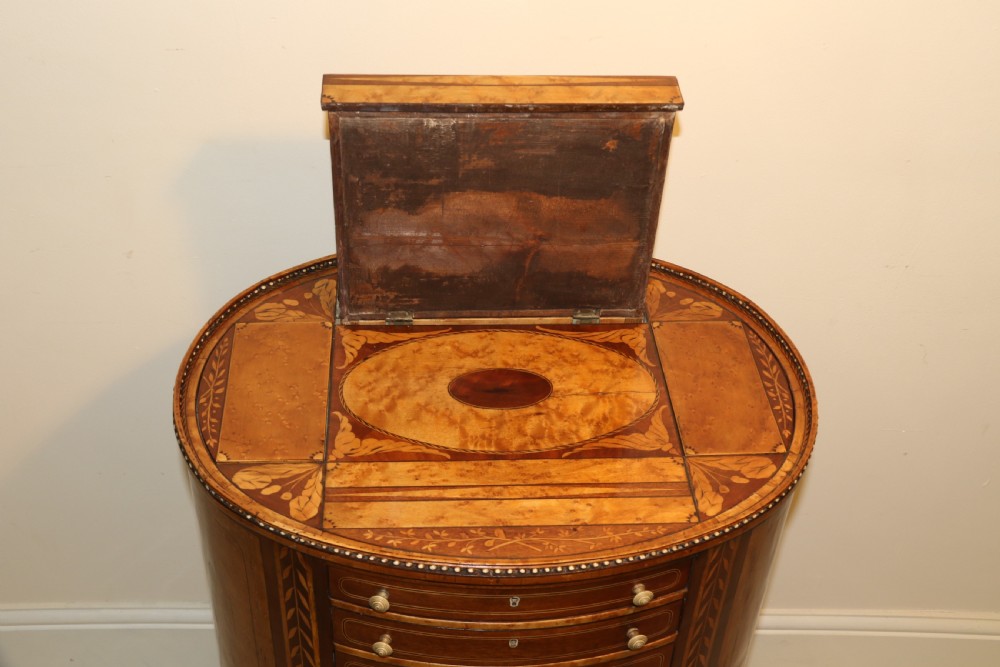 An oval George III satinwood worktable featuring marquetry inlay, multiple drawers, tapered legs, and a rising mirror compartment. View XIX