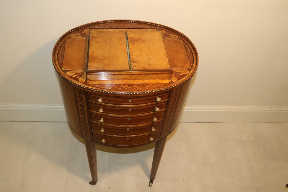 An oval George III satinwood worktable featuring marquetry inlay, multiple drawers, tapered legs, and a rising mirror compartment. View XXI