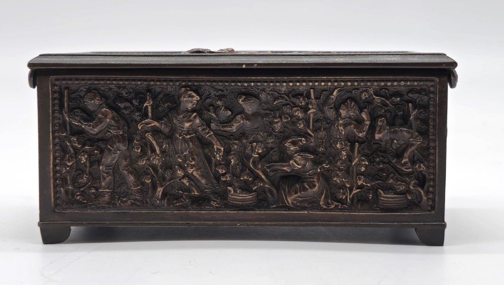 A rectangular dark patinated bronze jewellery casket featuring raised relief scenes on the sides and lid, accompanied by a small decorative key. View XII