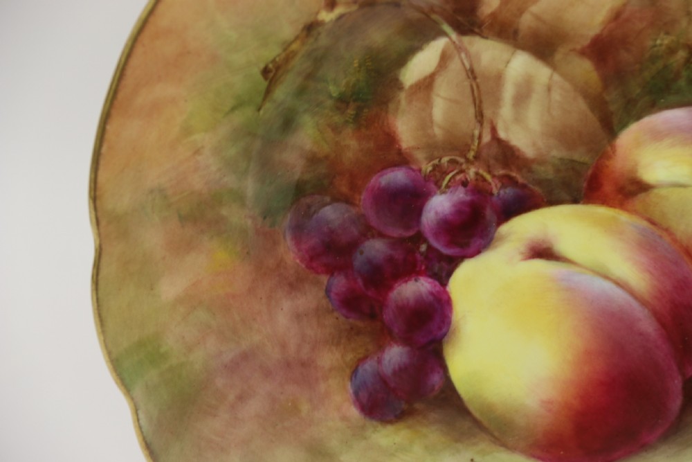 A pair of circular hand-painted porcelain plates displaying still life compositions of peaches, grapes, and blackberries framed by gilded scalloped edges. View III