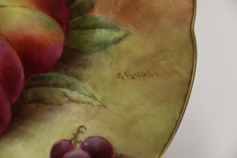 A pair of circular hand-painted porcelain plates displaying still life compositions of peaches, grapes, and blackberries framed by gilded scalloped edges. View V