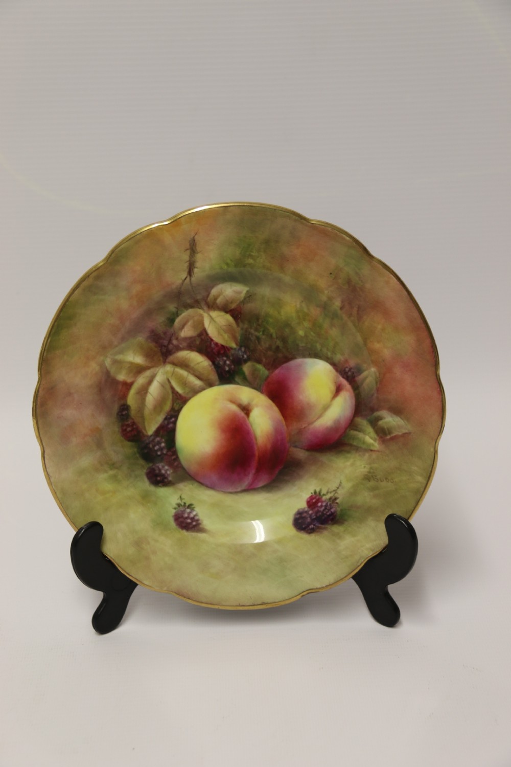 A pair of circular hand-painted porcelain plates displaying still life compositions of peaches, grapes, and blackberries framed by gilded scalloped edges. View VIII