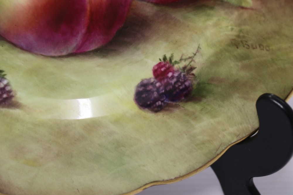 A pair of circular hand-painted porcelain plates displaying still life compositions of peaches, grapes, and blackberries framed by gilded scalloped edges. View XII