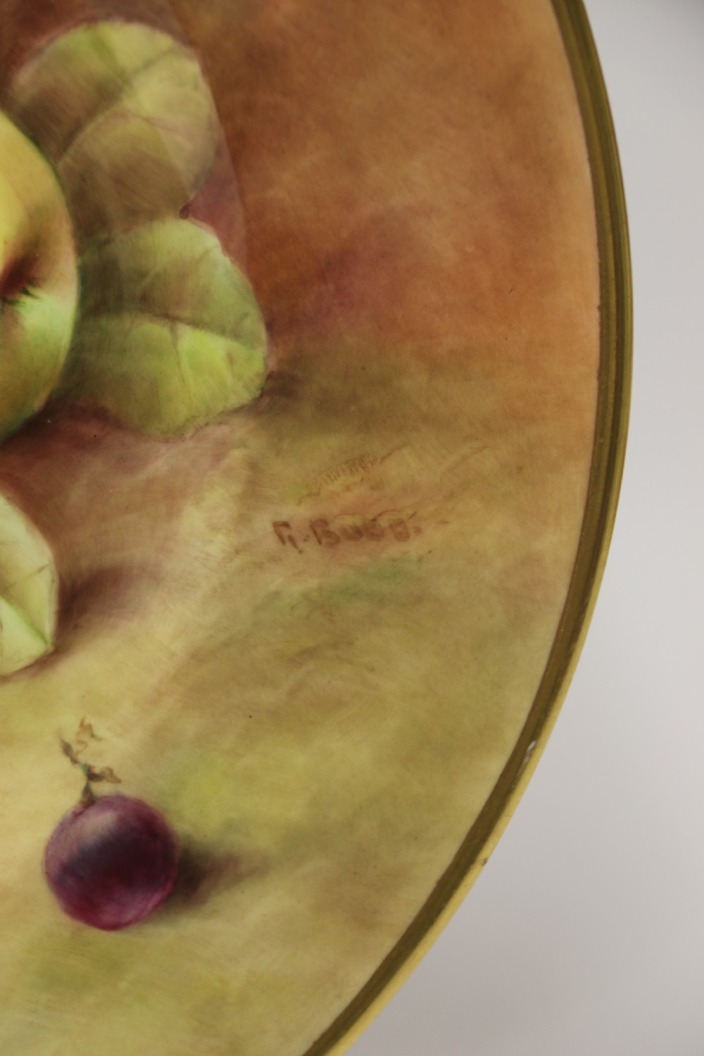 A pair of circular hand-painted porcelain plates displaying still life compositions of peaches, grapes, and blackberries framed by gilded scalloped edges. View XVIII