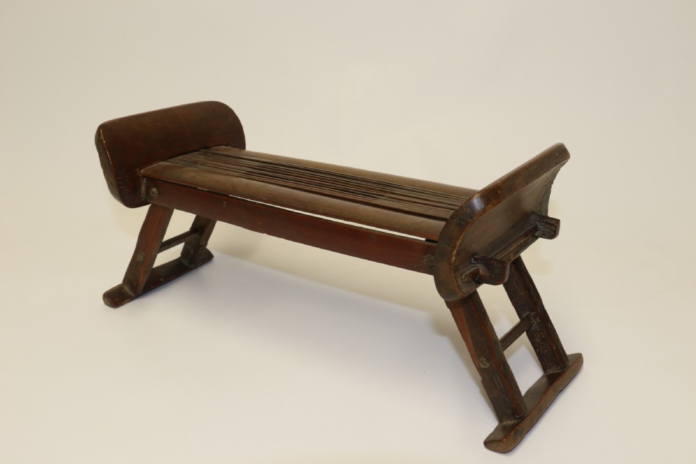 An eighteenth-century Chinese folding headrest crafted from dark bamboo and carved timber supports. View II