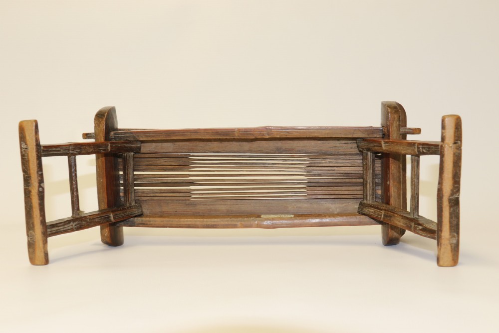 An eighteenth-century Chinese folding headrest crafted from dark bamboo and carved timber supports. View XVI