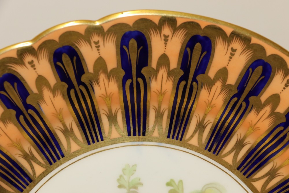 A pair of circular antique porcelain cabinet plates featuring central hand-painted floral motifs surrounded by elaborate gilded and cobalt blue borders. View VII