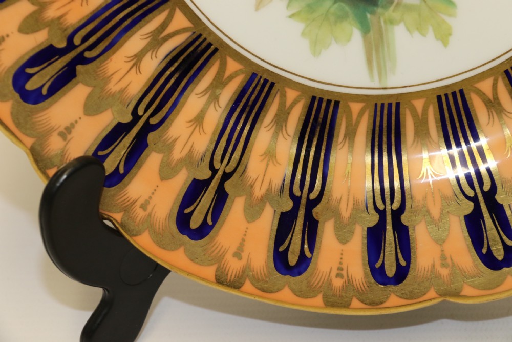 A pair of circular antique porcelain cabinet plates featuring central hand-painted floral motifs surrounded by elaborate gilded and cobalt blue borders. View VIII