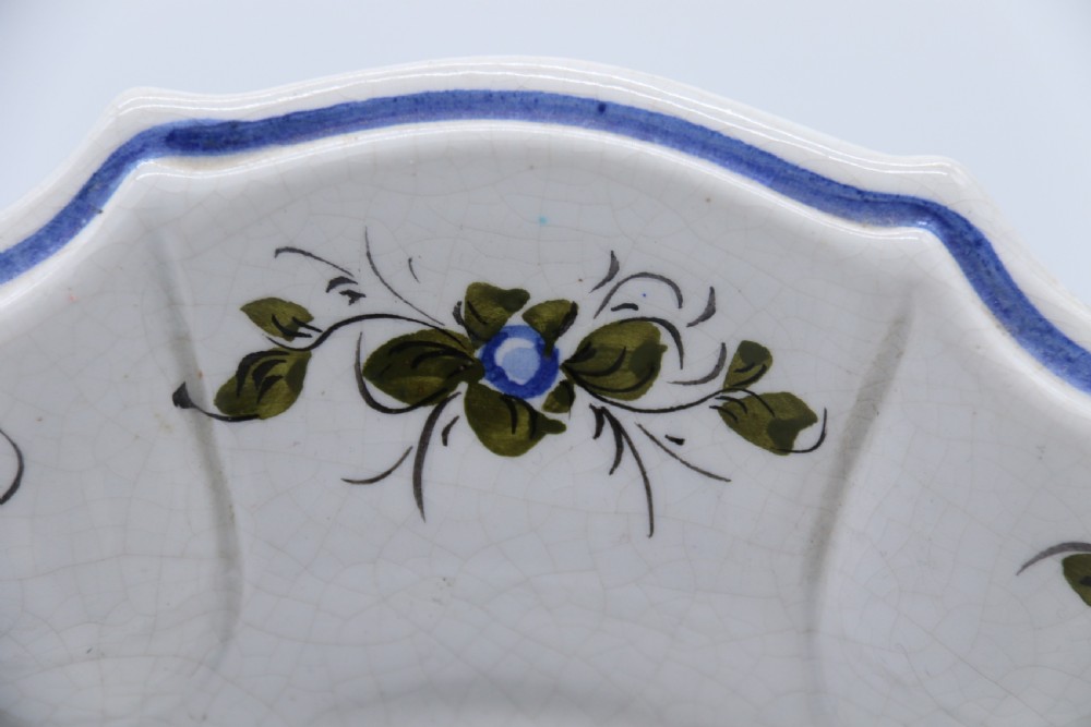 A circular tin-glazed earthenware wall charger featuring a hand-painted game bird in the centre surrounded by a scalloped, floral-decorated rim with blue edging. View VII