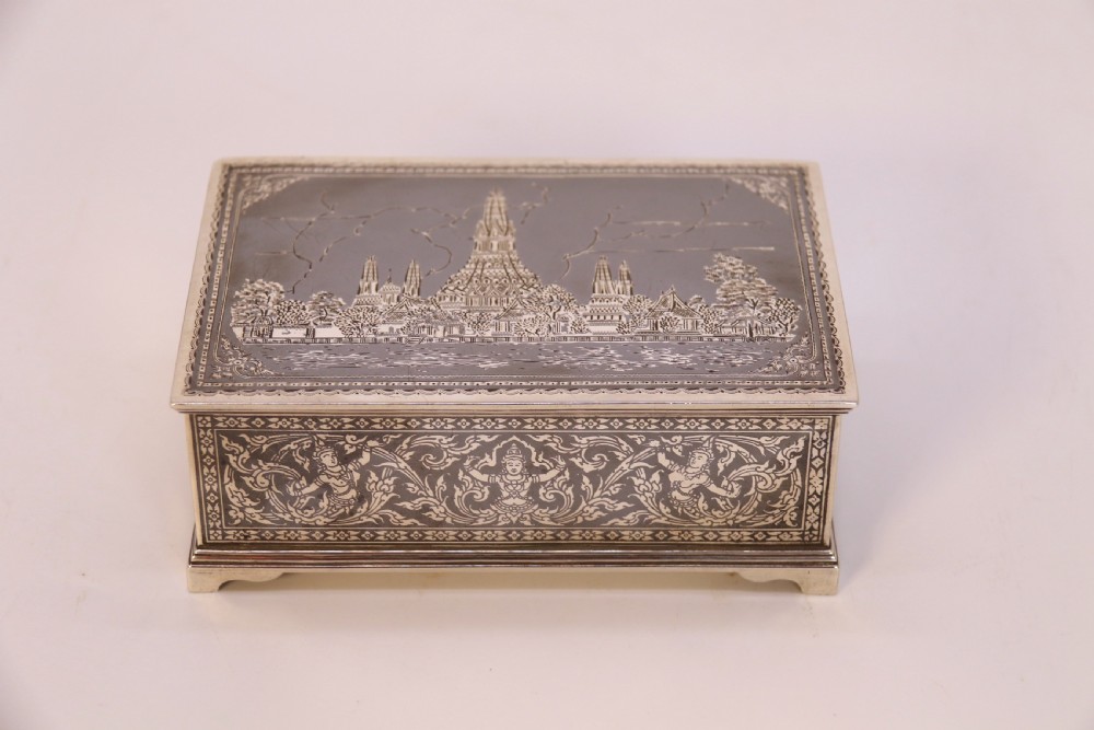 A rectangular sterling silver box featuring intricate black niello inlay artwork depicting a Thai temple architectural landscape on the lid and mythological figures along the sides.