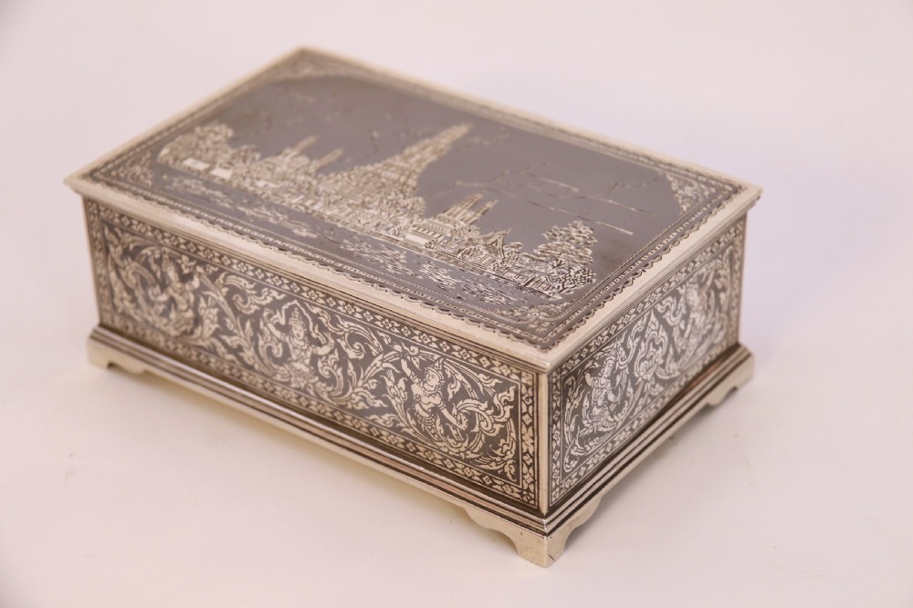 A rectangular sterling silver box featuring intricate black niello inlay artwork depicting a Thai temple architectural landscape on the lid and mythological figures along the sides. View II