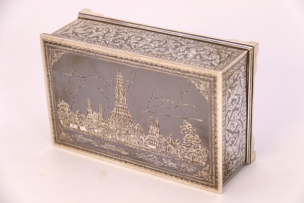 A rectangular sterling silver box featuring intricate black niello inlay artwork depicting a Thai temple architectural landscape on the lid and mythological figures along the sides. View IV