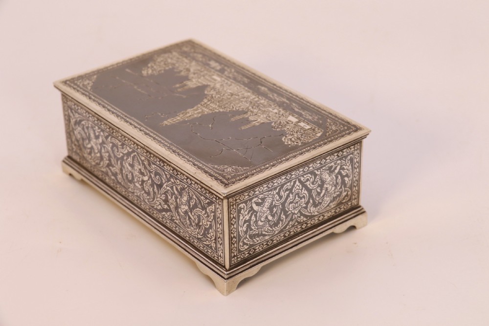 A rectangular sterling silver box featuring intricate black niello inlay artwork depicting a Thai temple architectural landscape on the lid and mythological figures along the sides. View V
