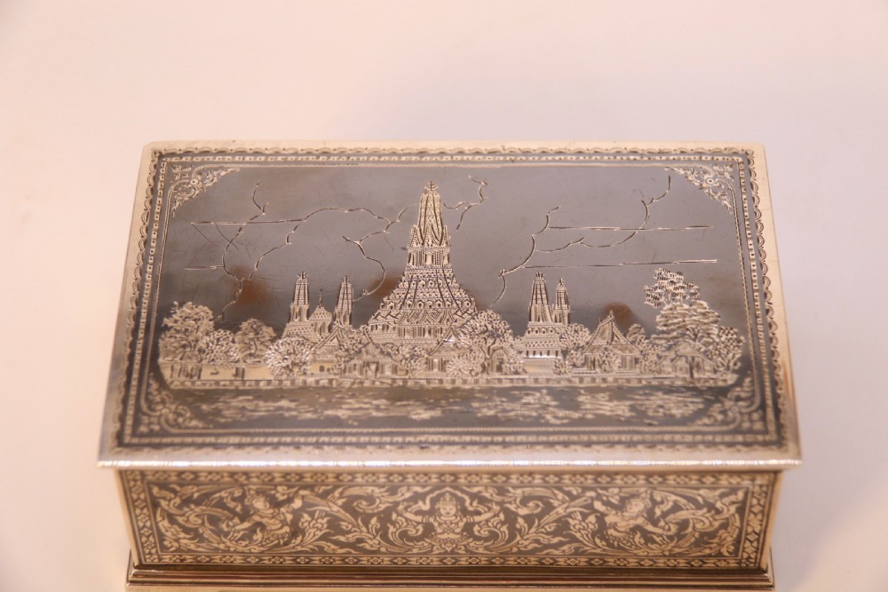 A rectangular sterling silver box featuring intricate black niello inlay artwork depicting a Thai temple architectural landscape on the lid and mythological figures along the sides. View XI
