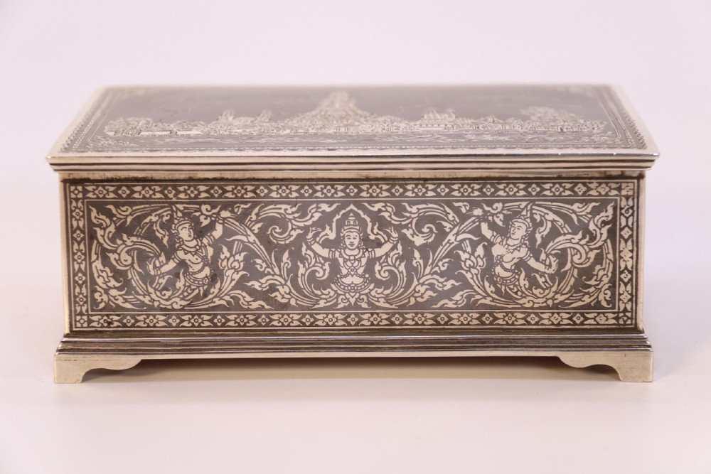 A rectangular sterling silver box featuring intricate black niello inlay artwork depicting a Thai temple architectural landscape on the lid and mythological figures along the sides. View XII