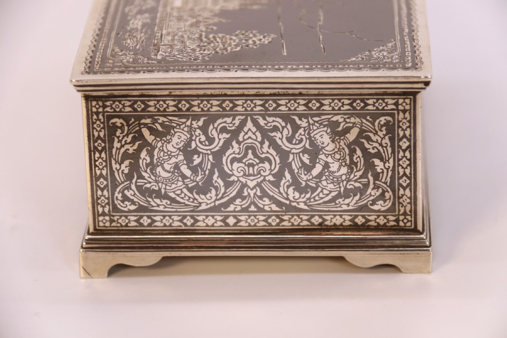 A rectangular sterling silver box featuring intricate black niello inlay artwork depicting a Thai temple architectural landscape on the lid and mythological figures along the sides. View XIII