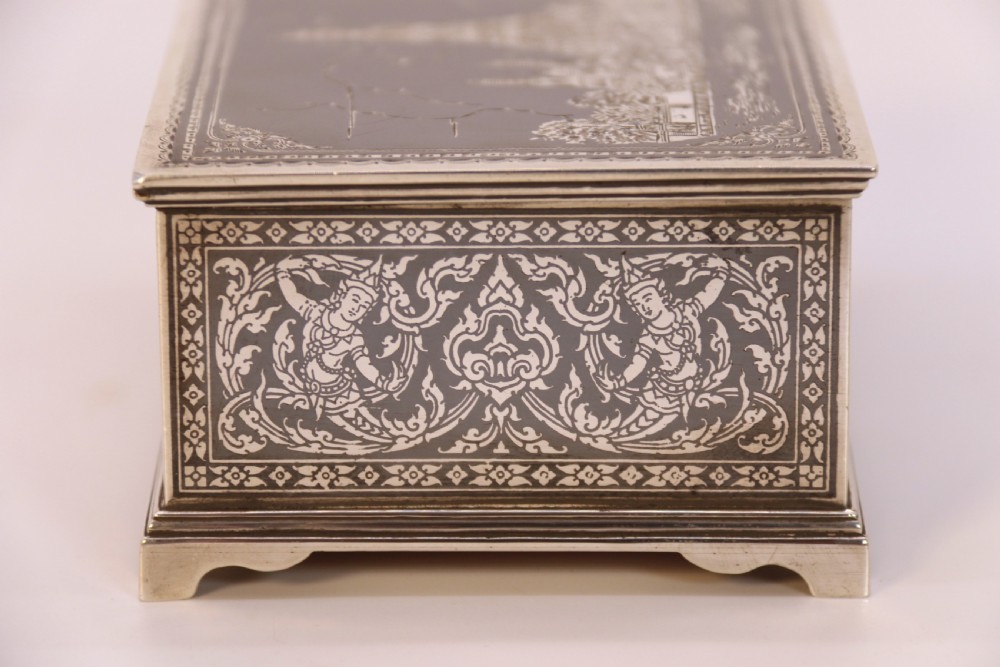 A rectangular sterling silver box featuring intricate black niello inlay artwork depicting a Thai temple architectural landscape on the lid and mythological figures along the sides. View XV