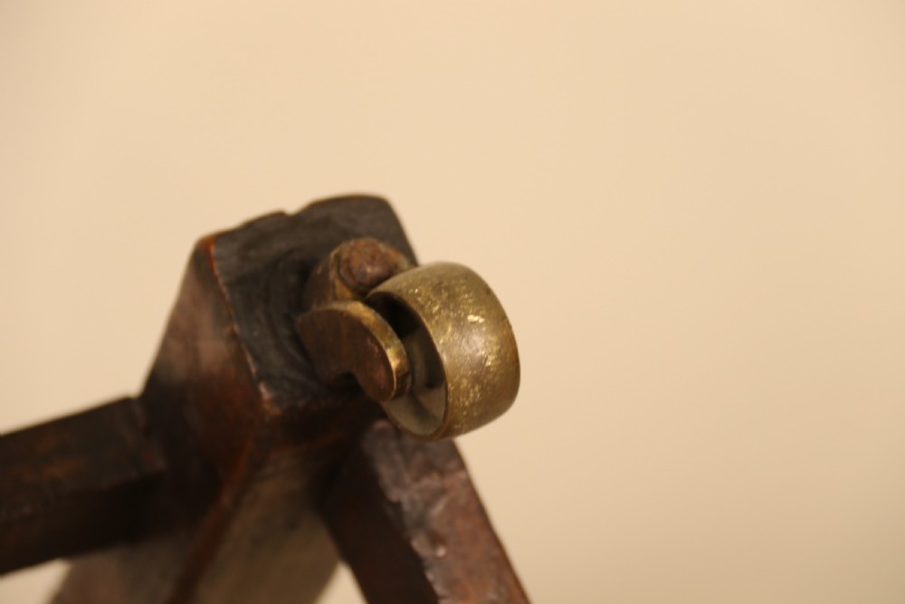 A George III chestnut brown leather wingback armchair featuring deep button tufting, brass stud detail, square wooden legs with stretchers, and brass castors. View XXII
