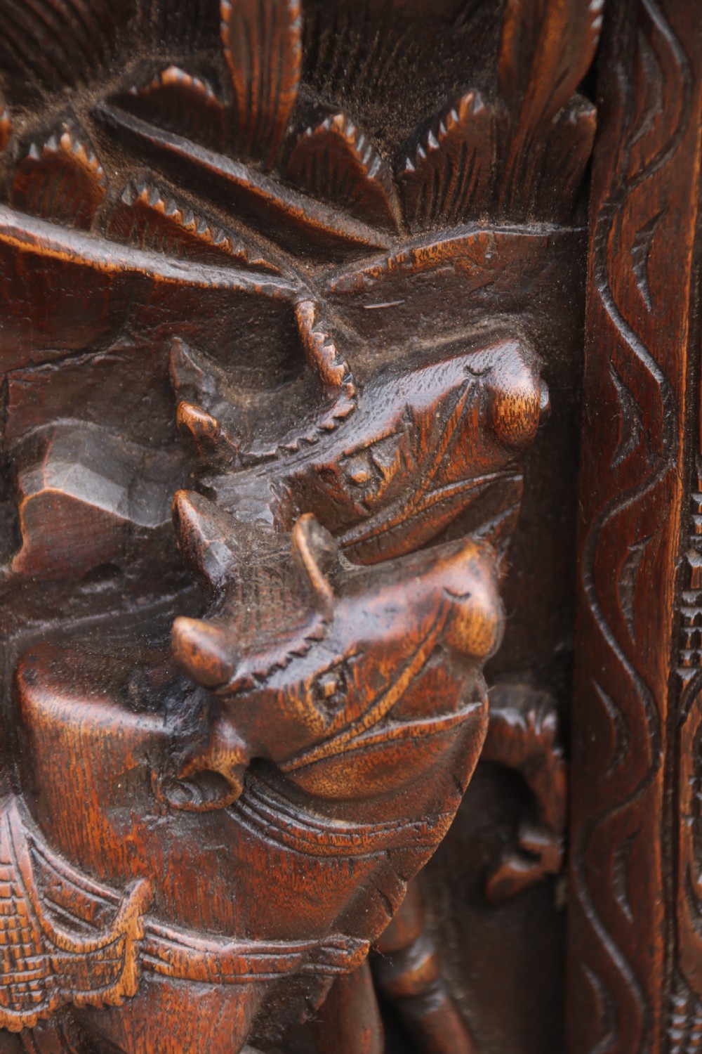 A dark hardwood rectangular panel featuring high-relief carvings of figures riding bullocks and a cart within an ornate carved border. View VII