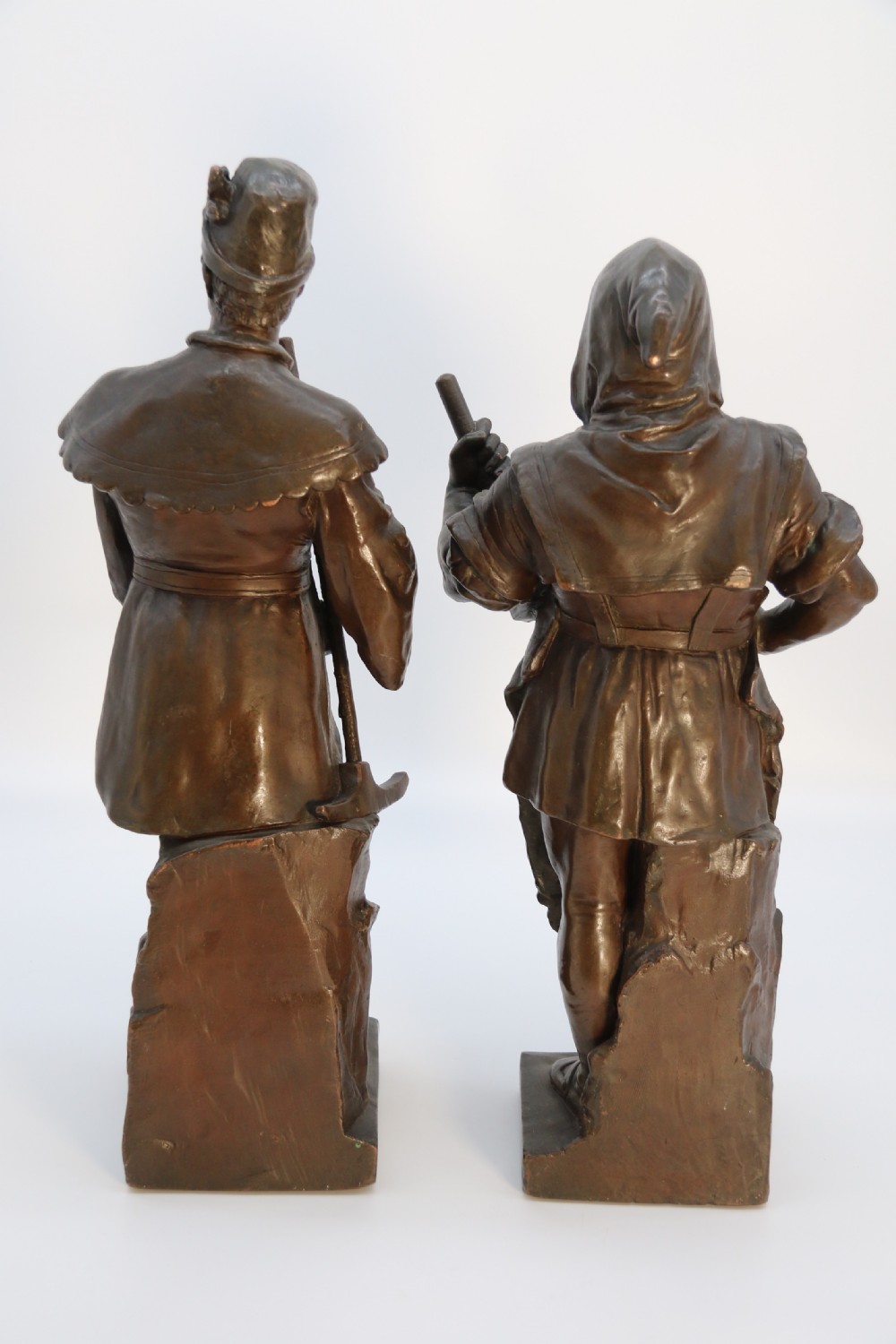 A pair of patinated electrotype bronze figures depicting historic tradesmen standing on rectangular plinths. View IV