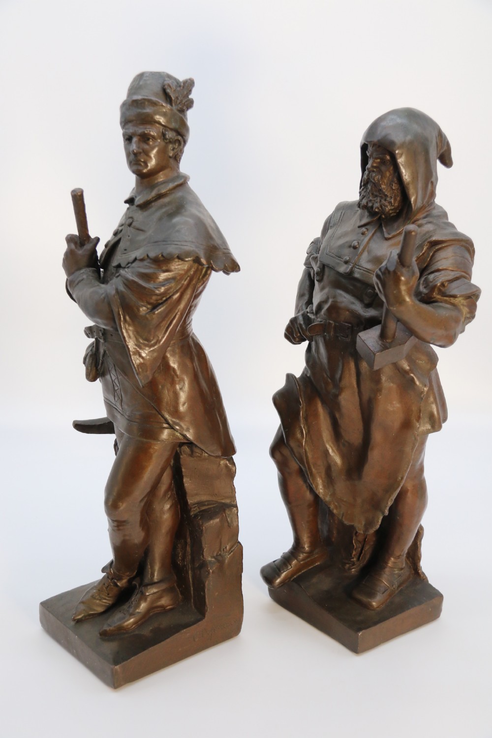 A pair of patinated electrotype bronze figures depicting historic tradesmen standing on rectangular plinths. View VII