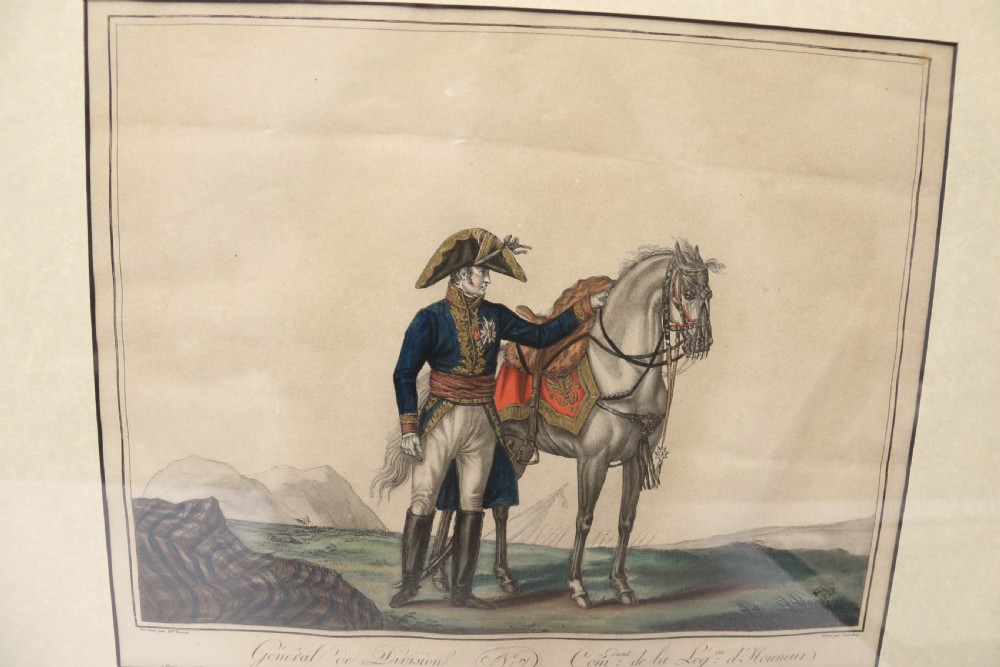 A framed early nineteenth-century hand-coloured print depicting a French Napoleonic military officer standing beside a grey horse in a landscape. View II