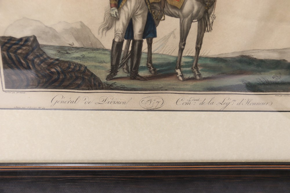 A framed early nineteenth-century hand-coloured print depicting a French Napoleonic military officer standing beside a grey horse in a landscape. View III
