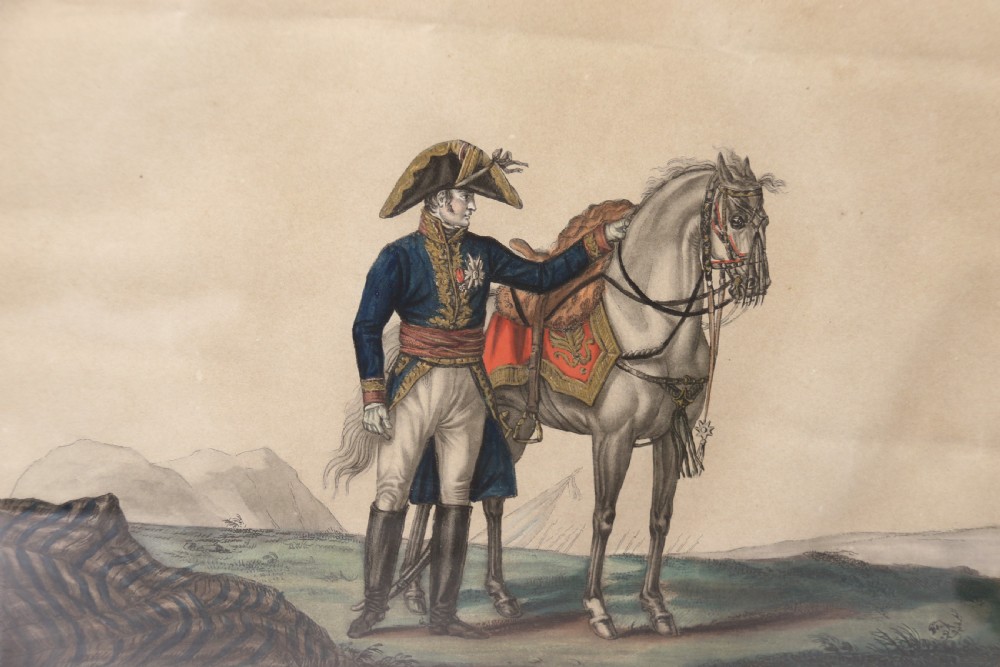 A framed early nineteenth-century hand-coloured print depicting a French Napoleonic military officer standing beside a grey horse in a landscape. View IX