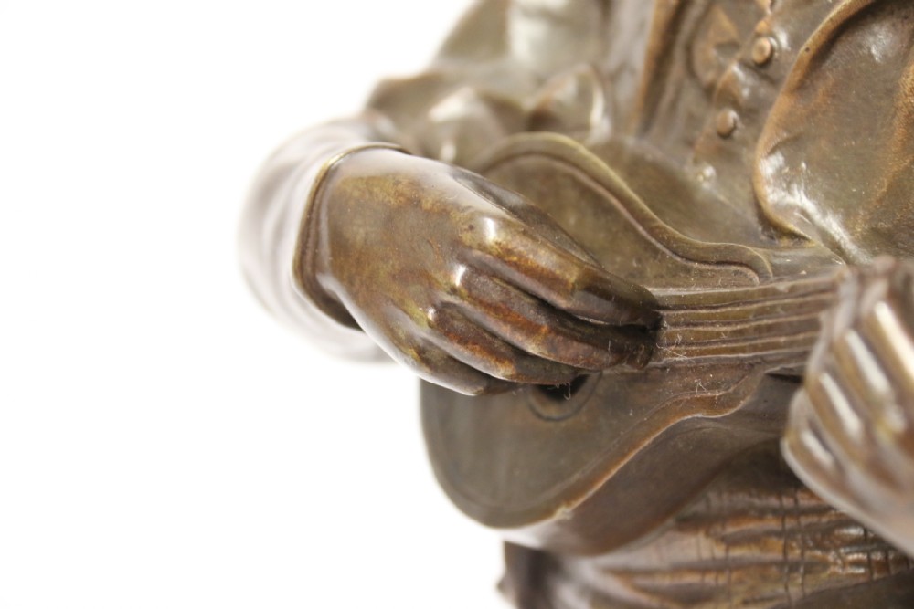 A patinated dark brown bronze sculpture depicting a standing male musician playing a mandolin while wearing a draped coat and headwear. View XIX