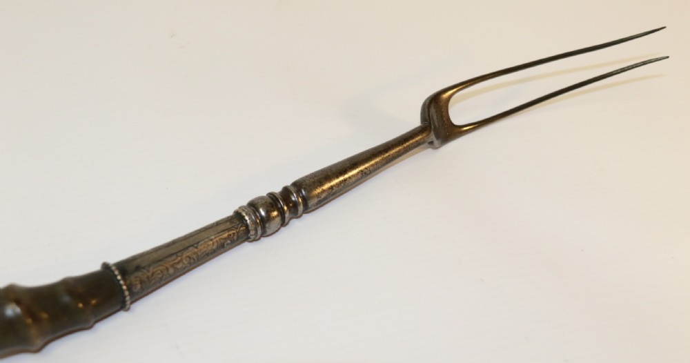 An early nineteenth-century roasting fork featuring a long, spiral horn handle with engraved silver mounts and a two-pronged steel tip. View V