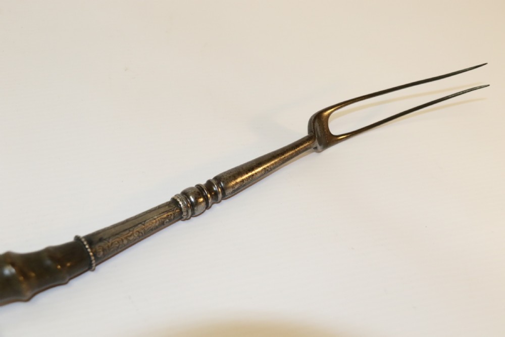 An early nineteenth-century roasting fork featuring a long, spiral horn handle with engraved silver mounts and a two-pronged steel tip. View VI