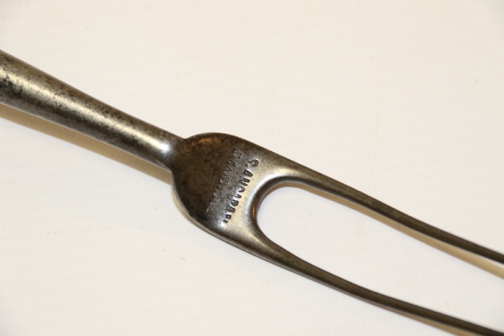An early nineteenth-century roasting fork featuring a long, spiral horn handle with engraved silver mounts and a two-pronged steel tip. View IX