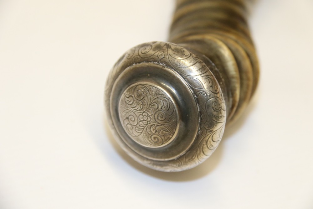 An early nineteenth-century roasting fork featuring a long, spiral horn handle with engraved silver mounts and a two-pronged steel tip. View X
