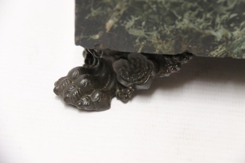 An Empire period dark green marble inkstand featuring dark patinated bronze cherub figures, twin urn inkwells, and carved claw feet. View III