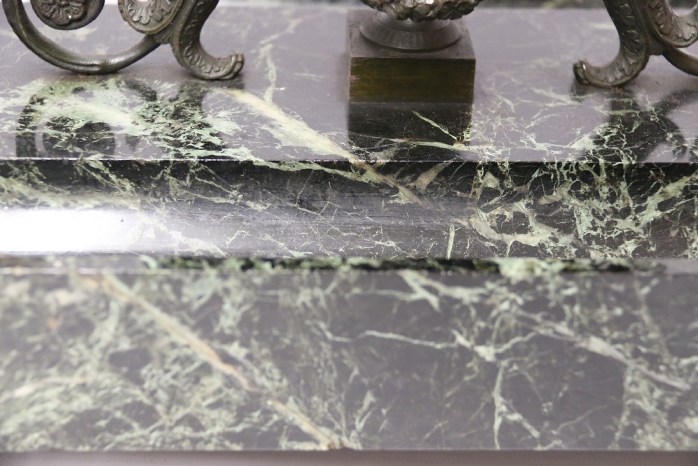 An Empire period dark green marble inkstand featuring dark patinated bronze cherub figures, twin urn inkwells, and carved claw feet. View V