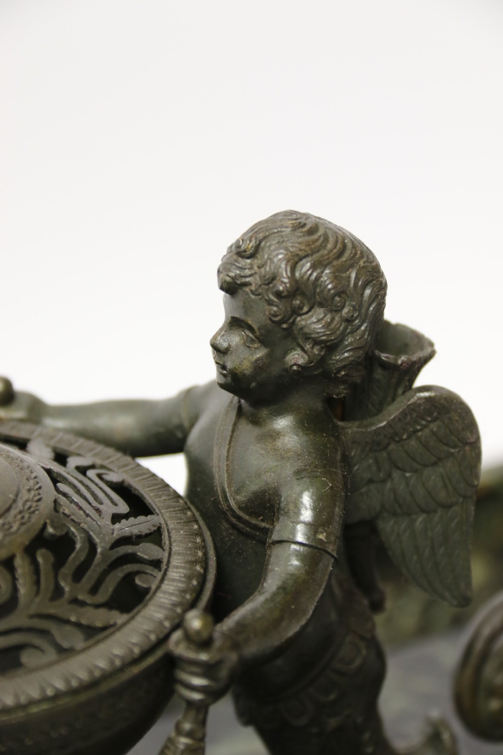 An Empire period dark green marble inkstand featuring dark patinated bronze cherub figures, twin urn inkwells, and carved claw feet. View XV
