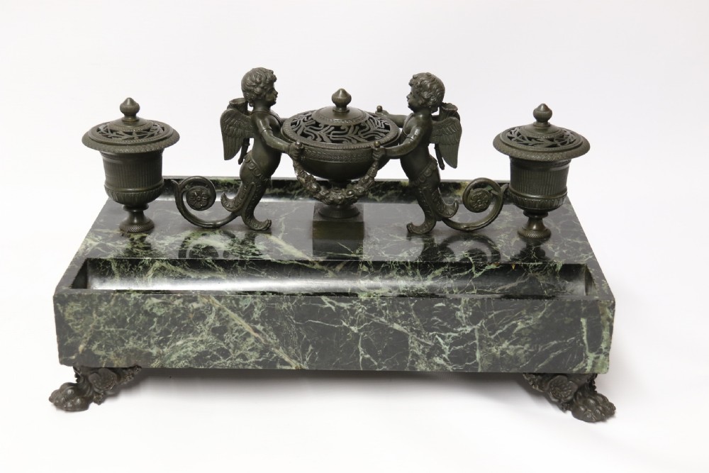 An Empire period dark green marble inkstand featuring dark patinated bronze cherub figures, twin urn inkwells, and carved claw feet. View XVI
